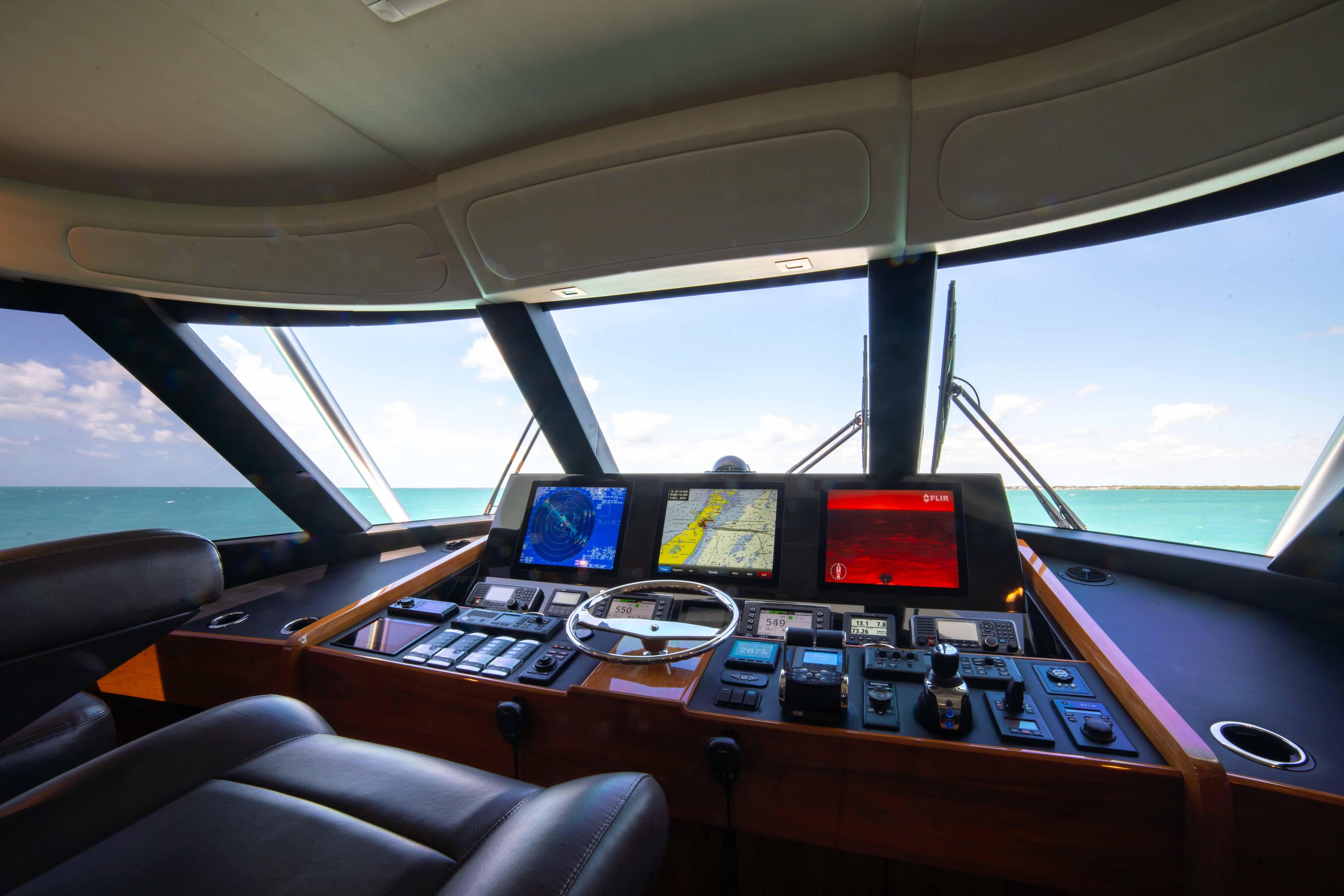 Interior view of 2019 Viking 72 Enclosed Bridge yacht's helm with navigation screens.