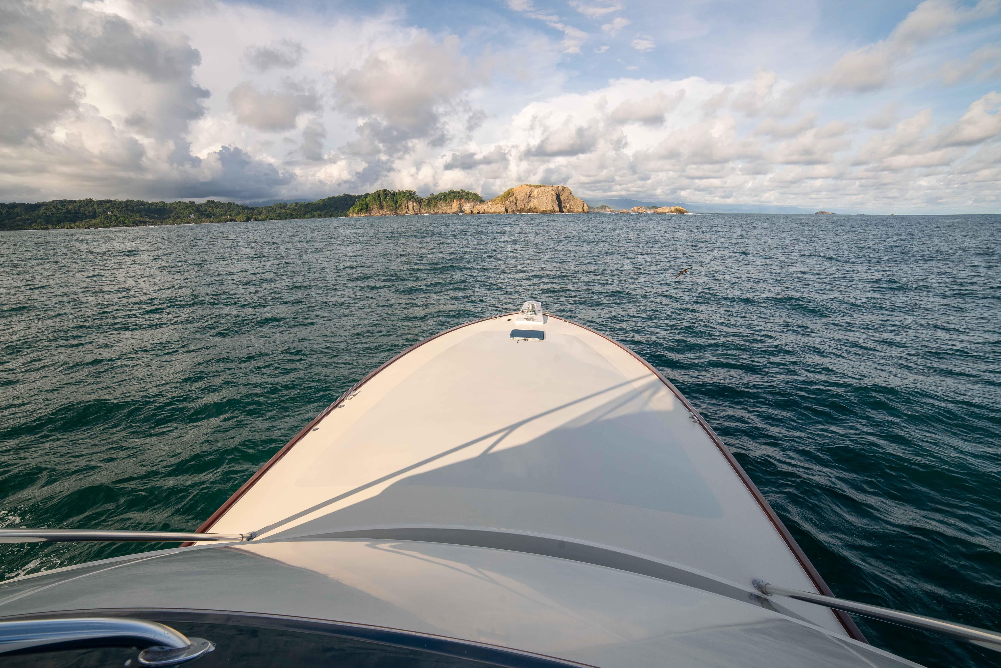 Bow view of 1996 Donzi 72 Custom Convertible yacht cruising towards rocky coastline.