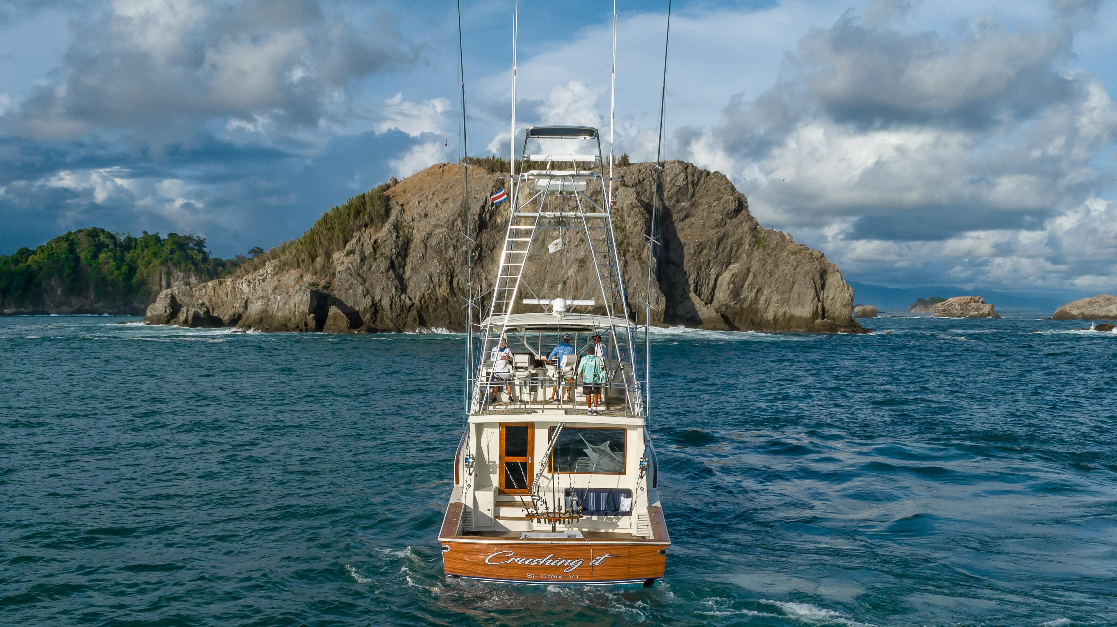 1996 Donzi 72 Custom Convertible yacht cruising near rocky island.