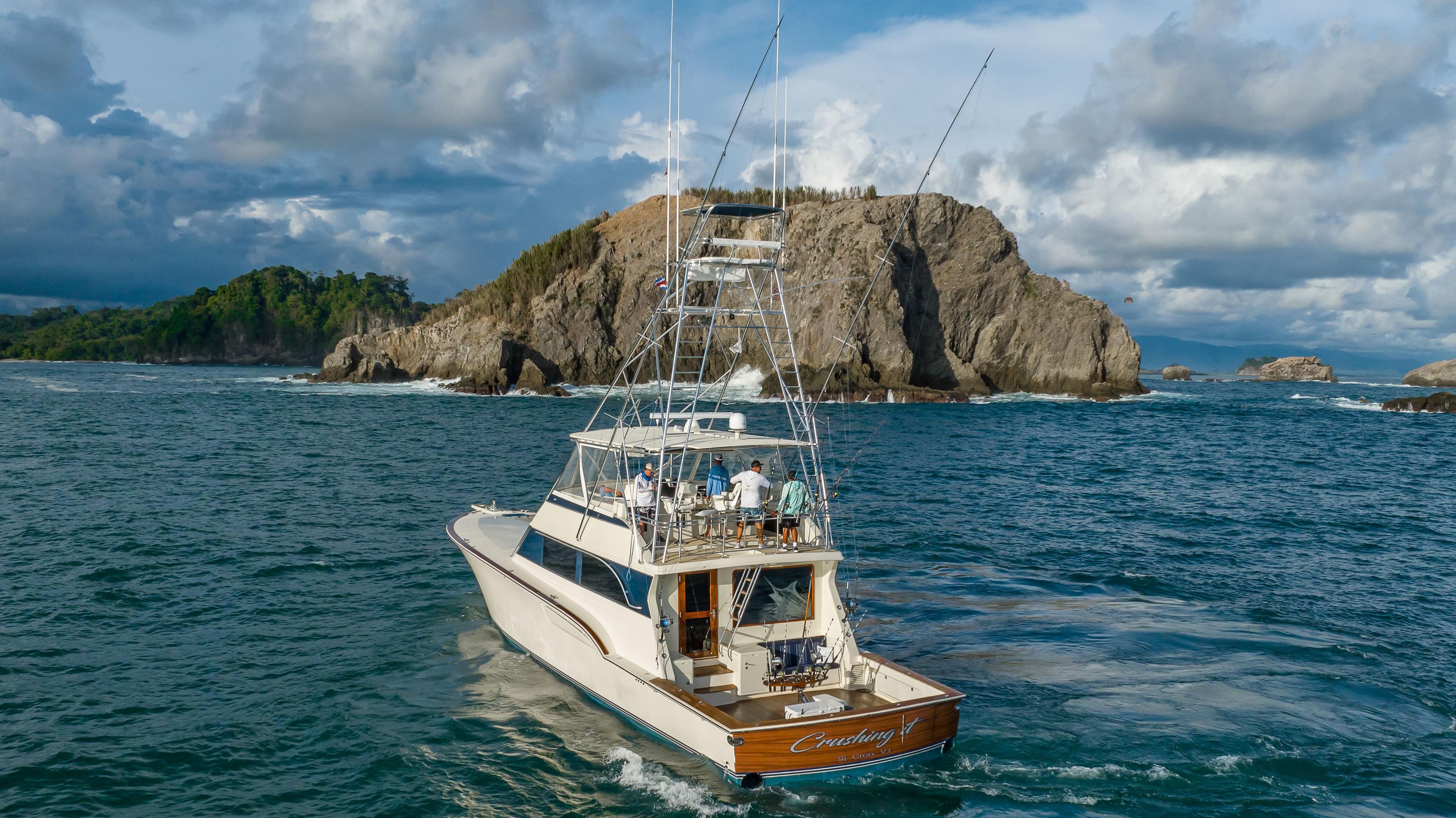 1996 Donzi 72 Custom Convertible yacht cruising near rocky island.