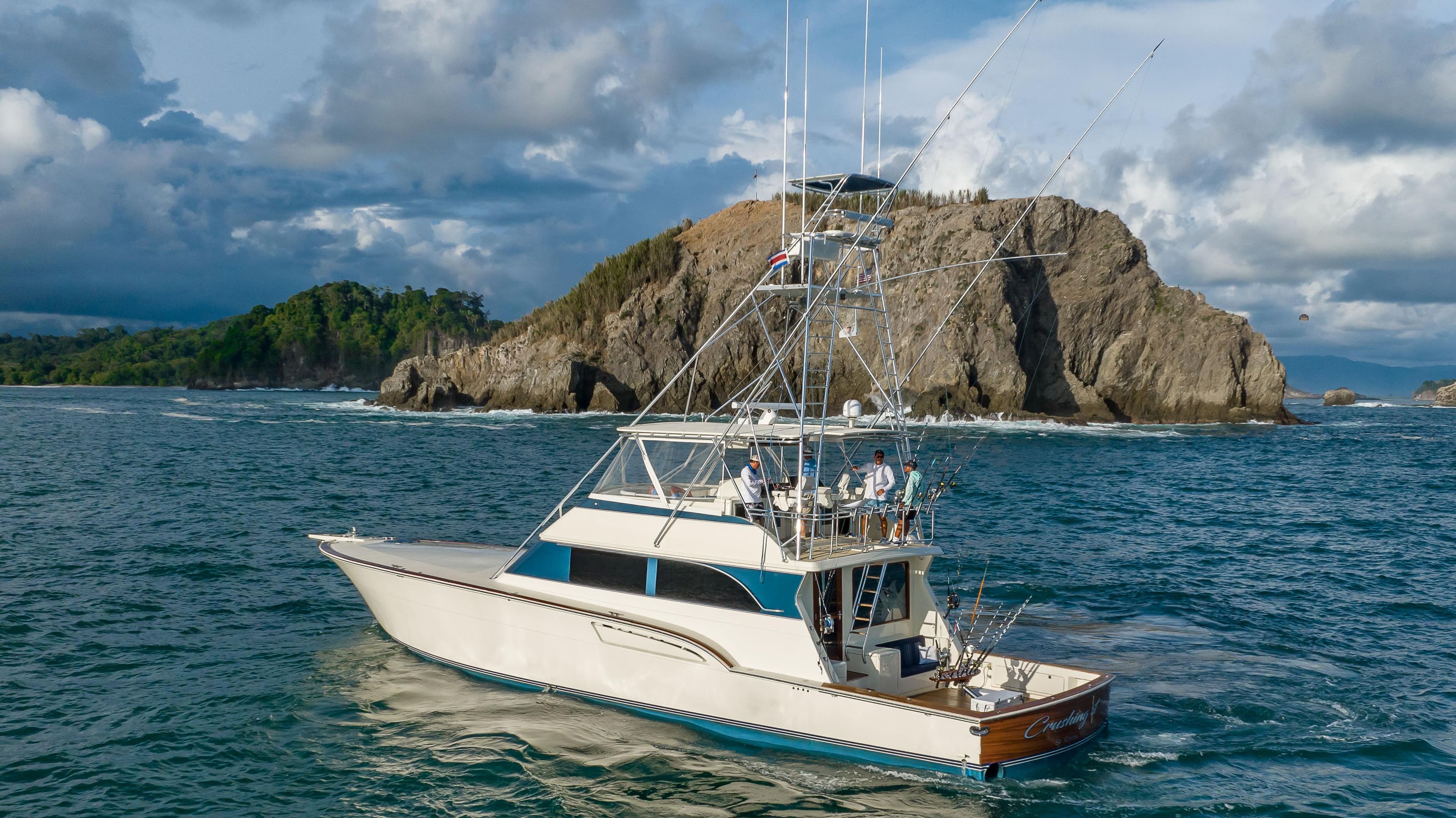 1996 Donzi 72 Custom Convertible yacht cruising near rocky island.