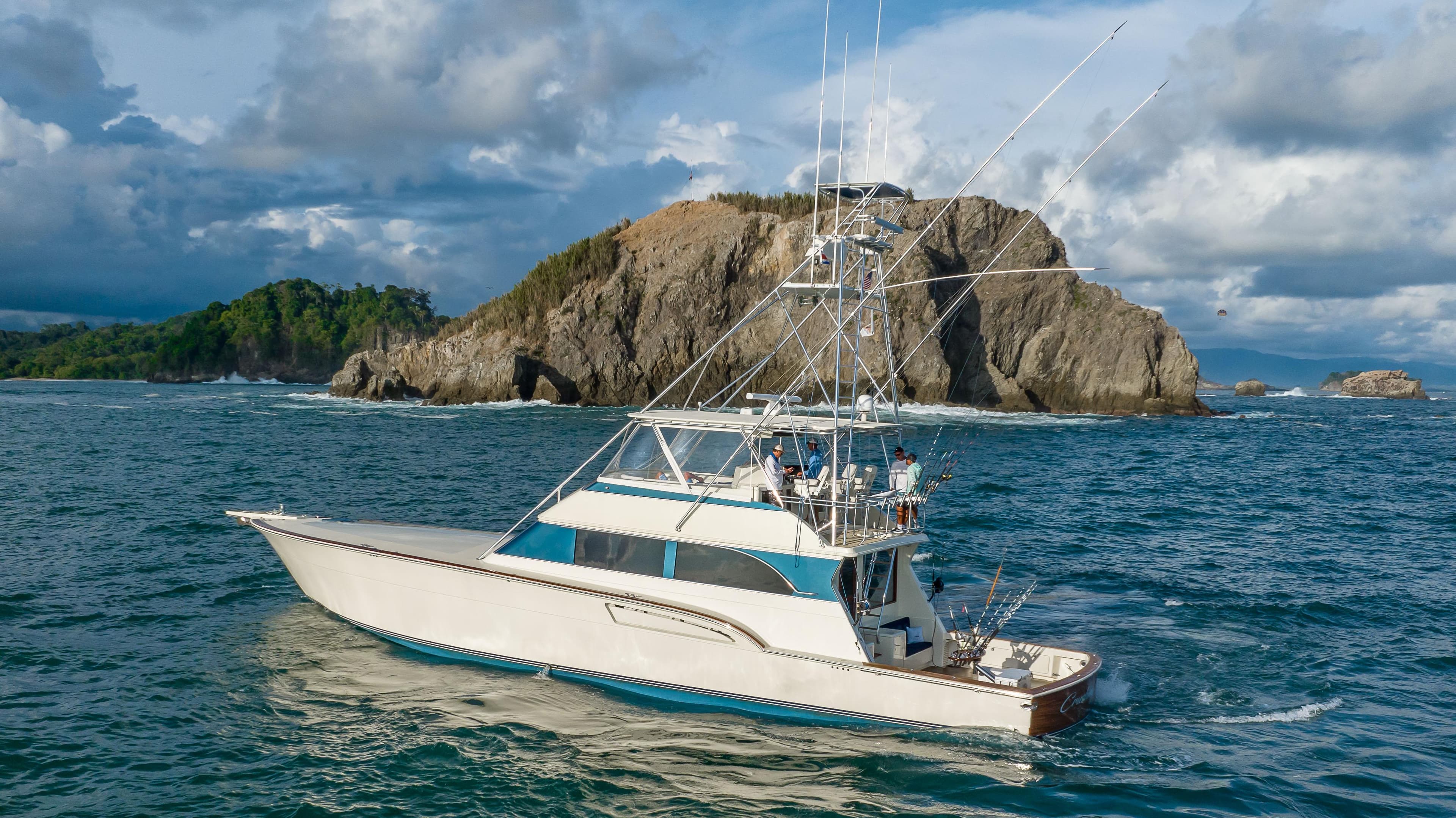 1996 Donzi 72 Custom Convertible yacht cruising near rocky island.