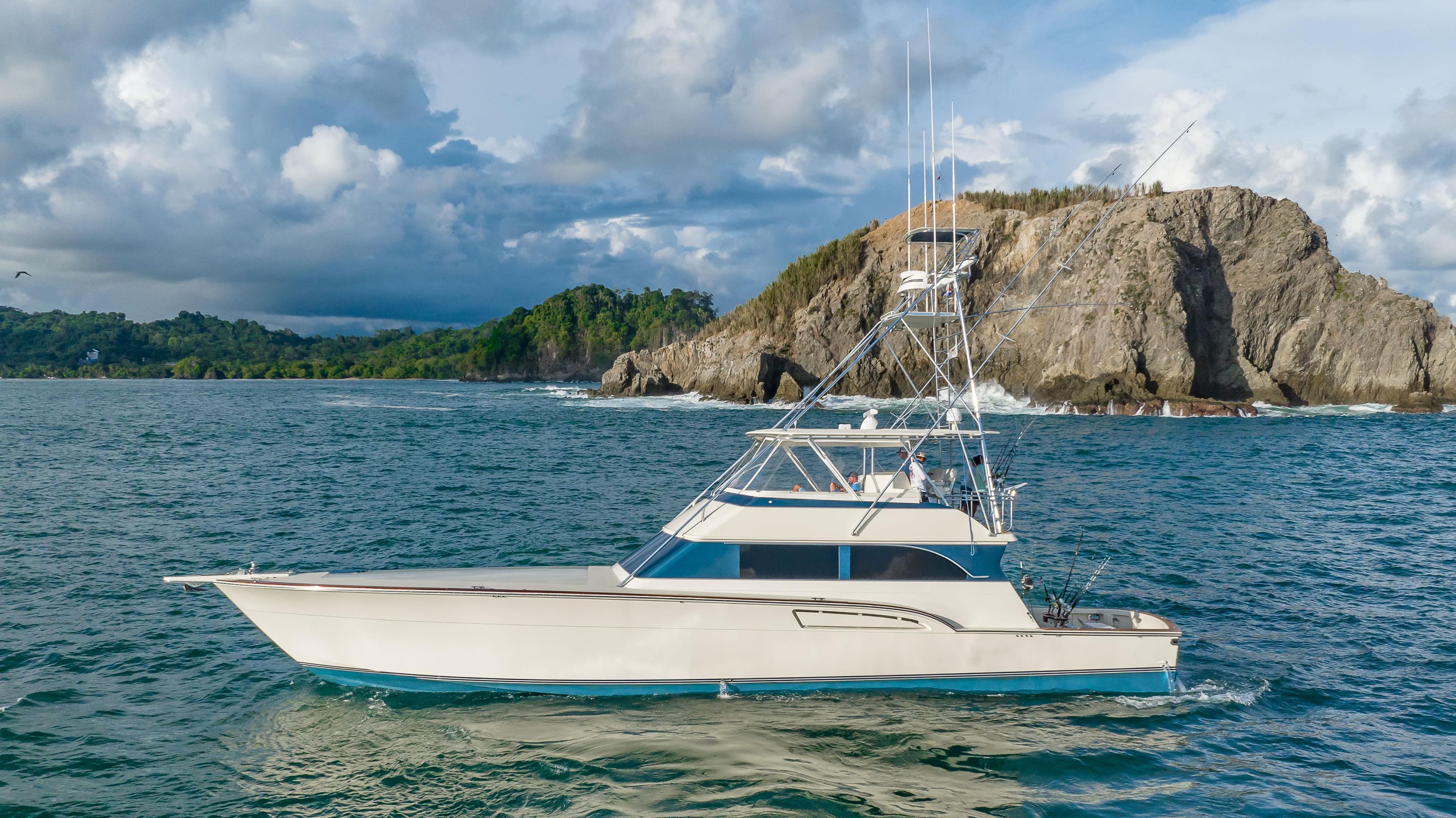 1996 Donzi 72 Custom Convertible yacht cruising near rocky coastline.