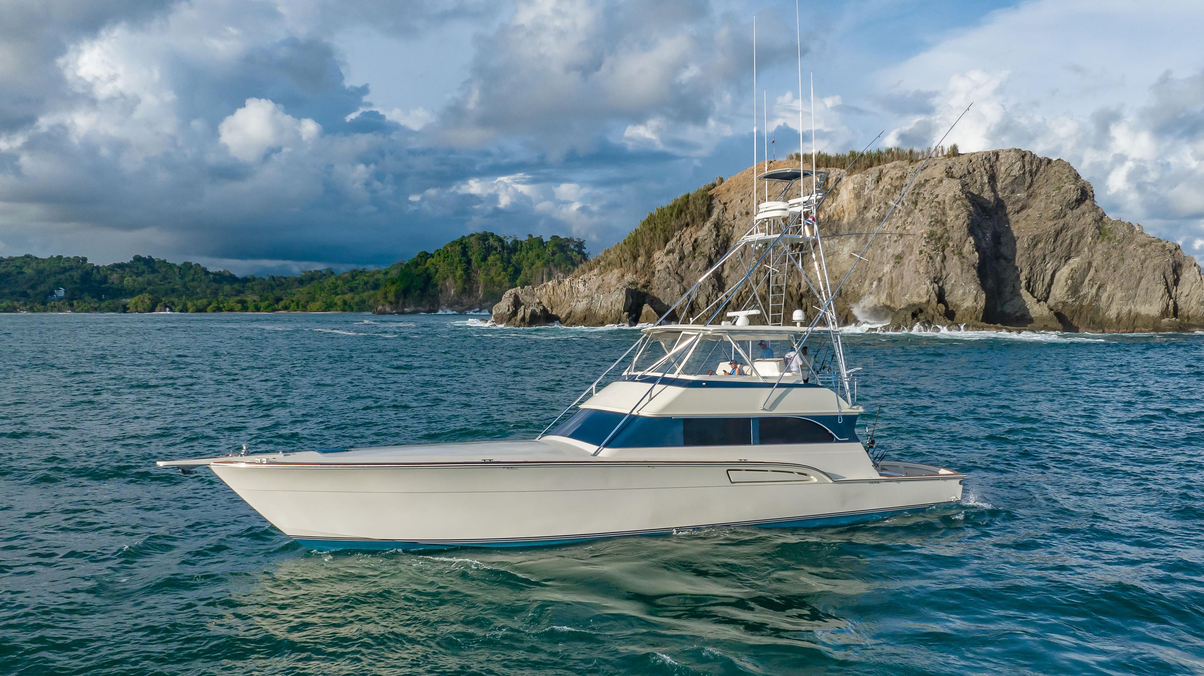 1996 Donzi 72 Custom Convertible yacht cruising near rocky coastline.