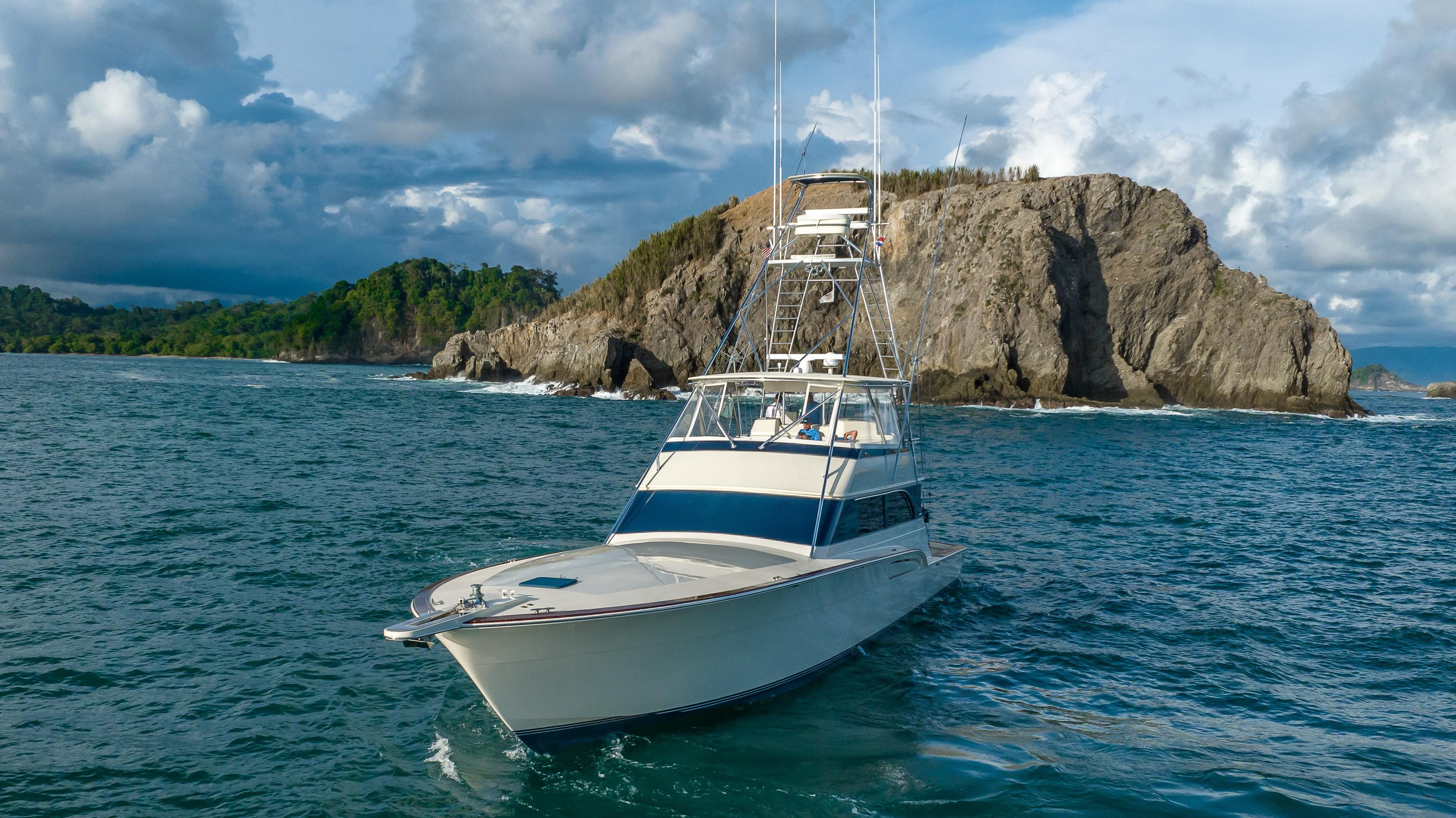 1996 Donzi 72 Custom Convertible yacht cruising near rocky coastline.