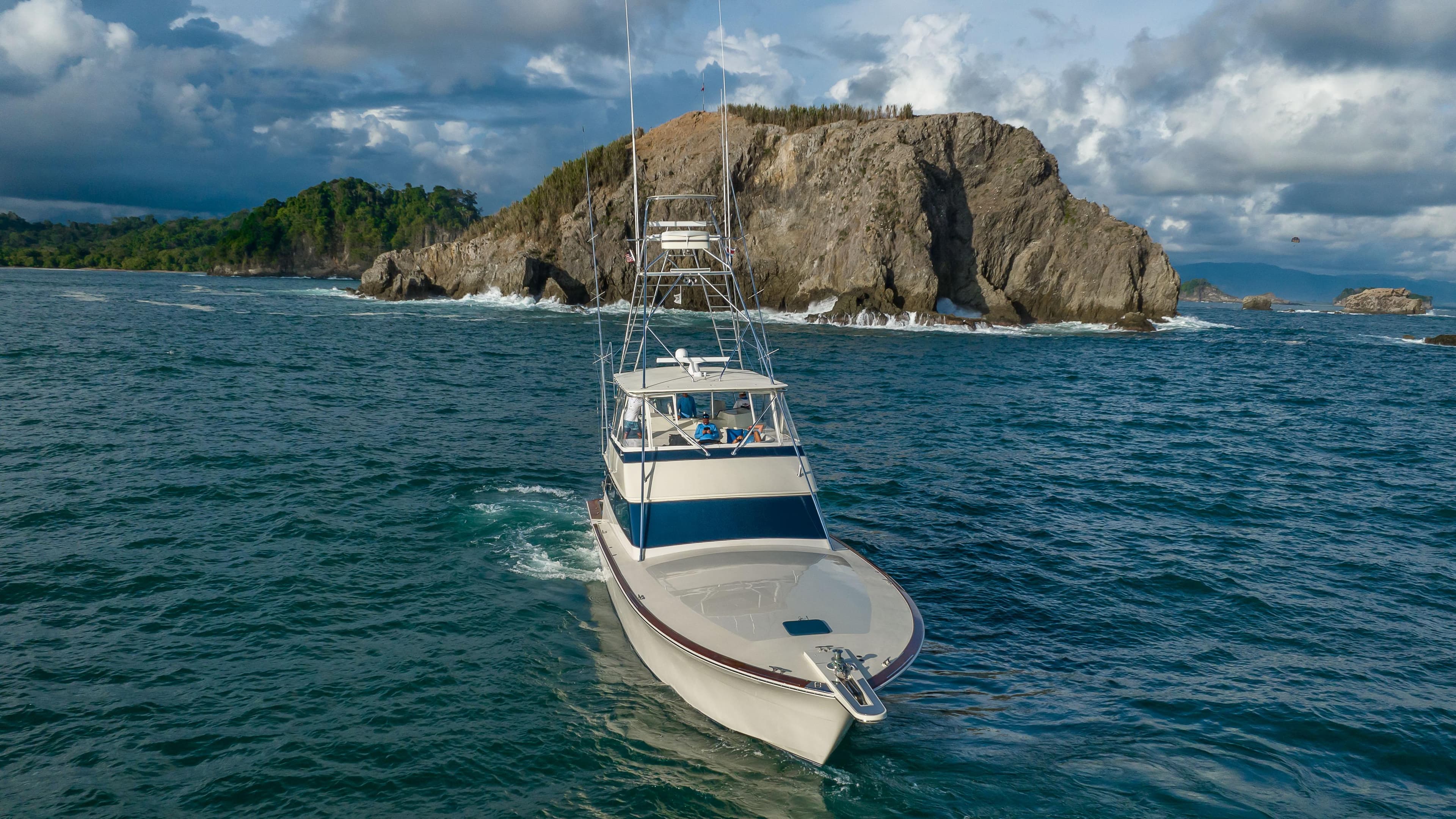 1996 Donzi 72 Custom Convertible yacht cruising near rocky island.
