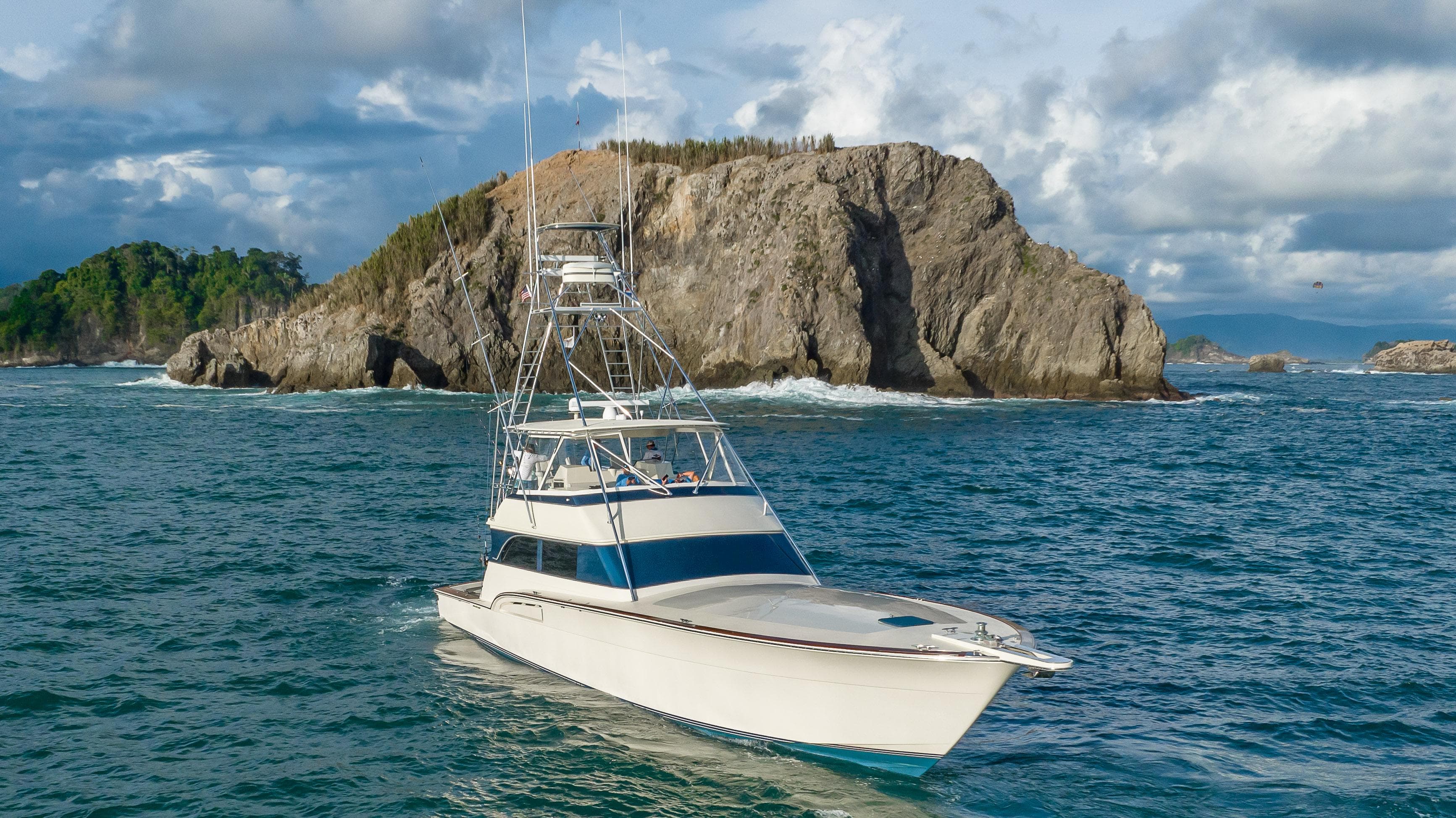 1996 Donzi 72 Custom Convertible yacht cruising near rocky island.
