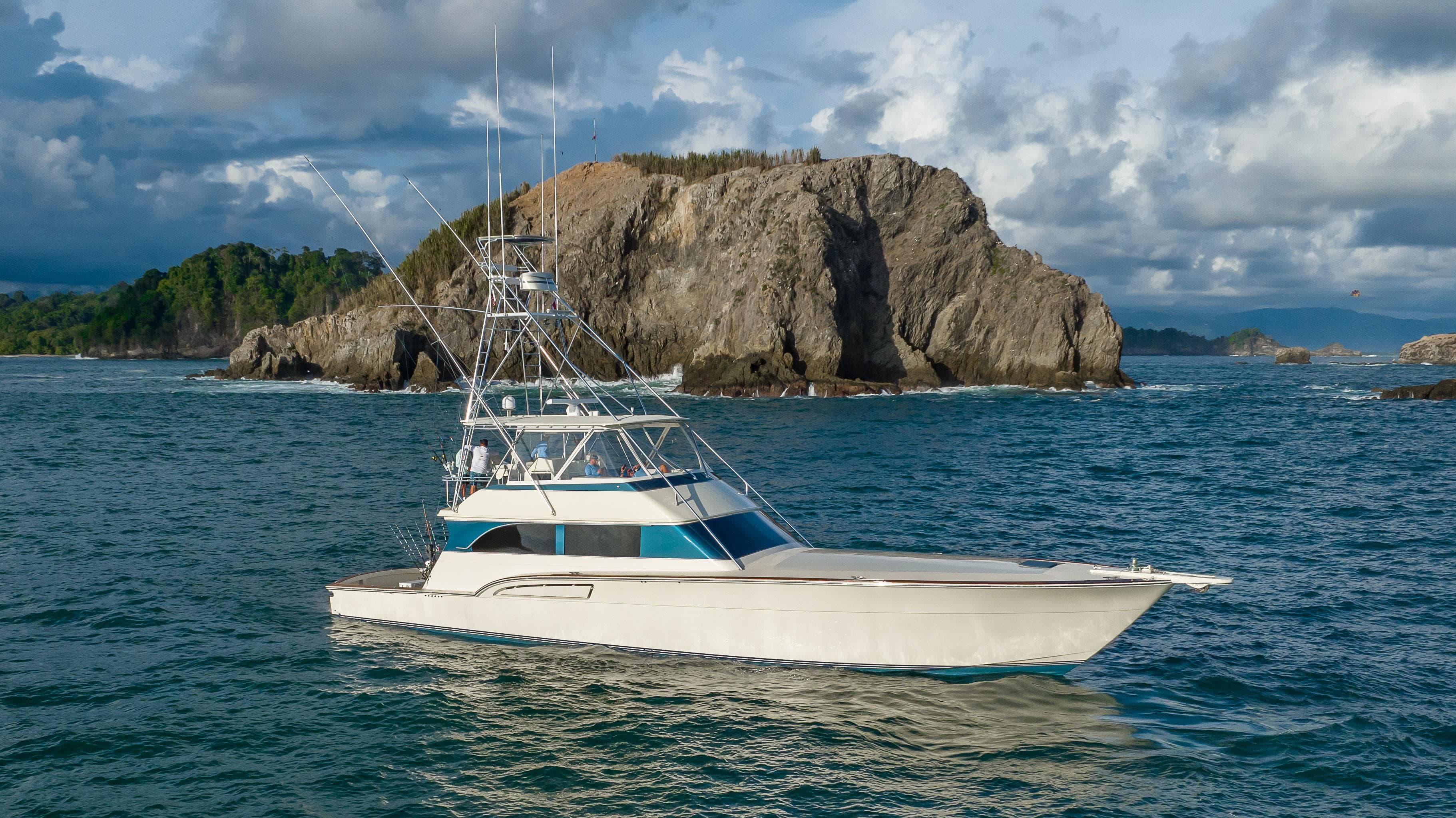 1996 Donzi 72 Custom Convertible yacht cruising near rocky coastline.