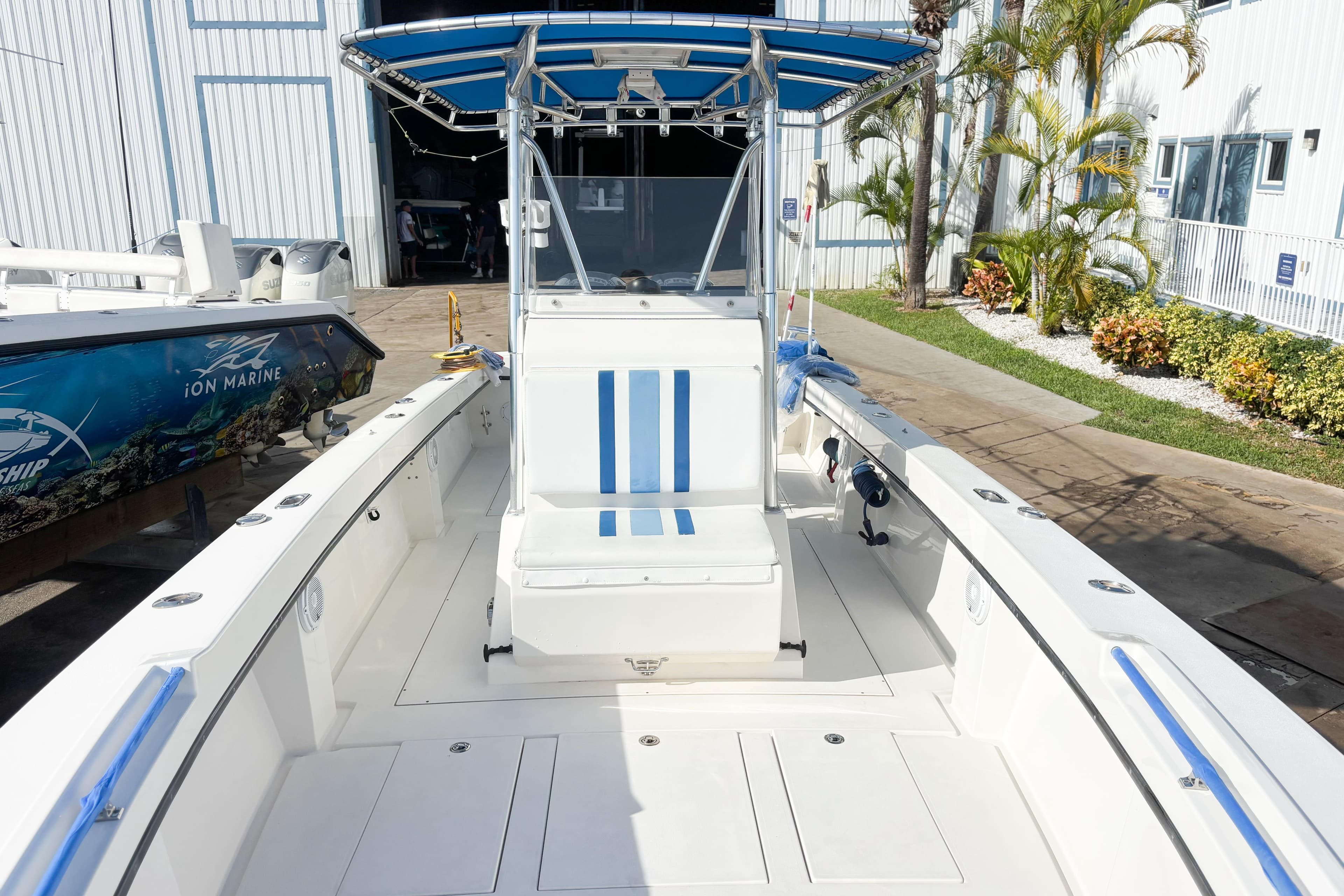 Whitewater 2016 boat with blue-striped seating and canopy, docked near a building.