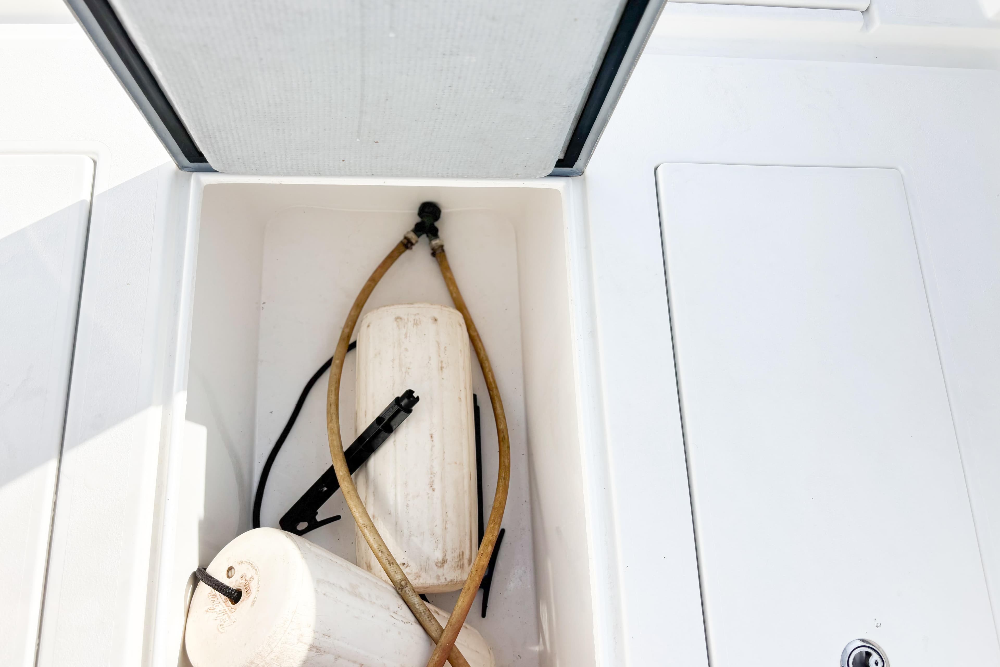 Storage compartment on a 2016 Whitewater boat with hoses and fenders.