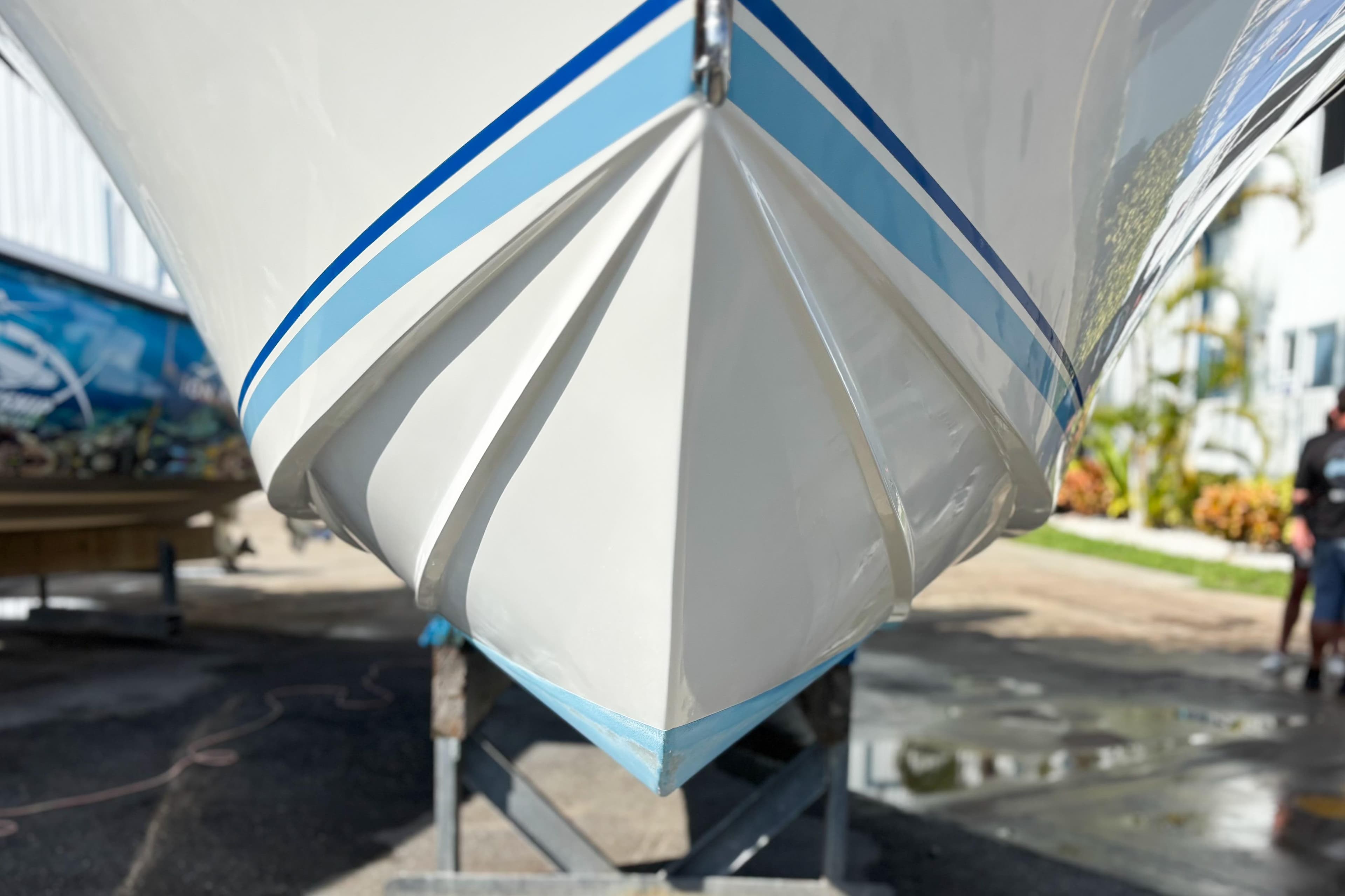 Close-up of a 2016 Whitewater boat hull with blue stripes, displayed outdoors.