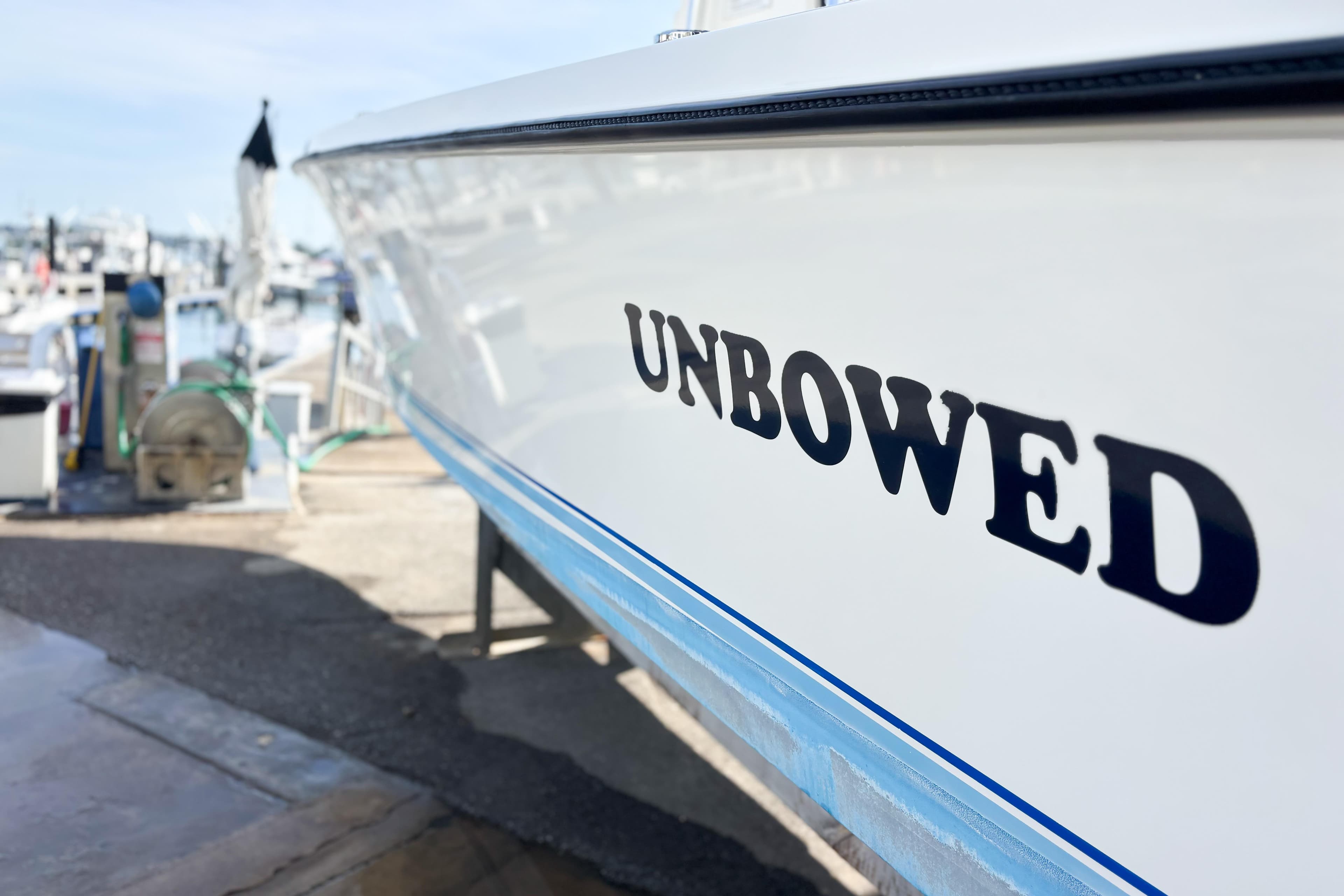 Whitewater boat named "Unbowed" docked, 2016 model, side view.
