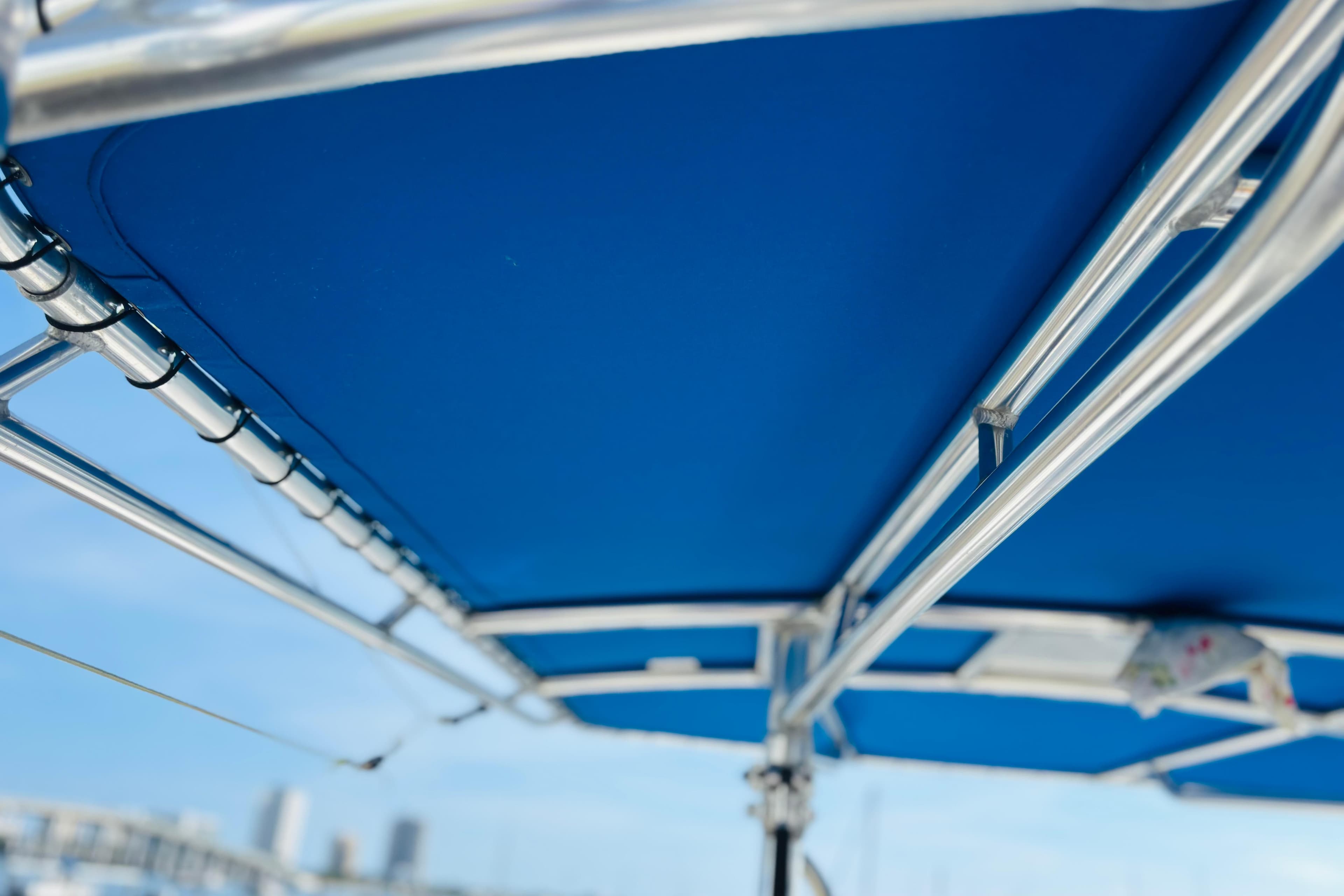 Blue boat canopy with metal frame, Whitewater make, 2016 model, clear sky background.