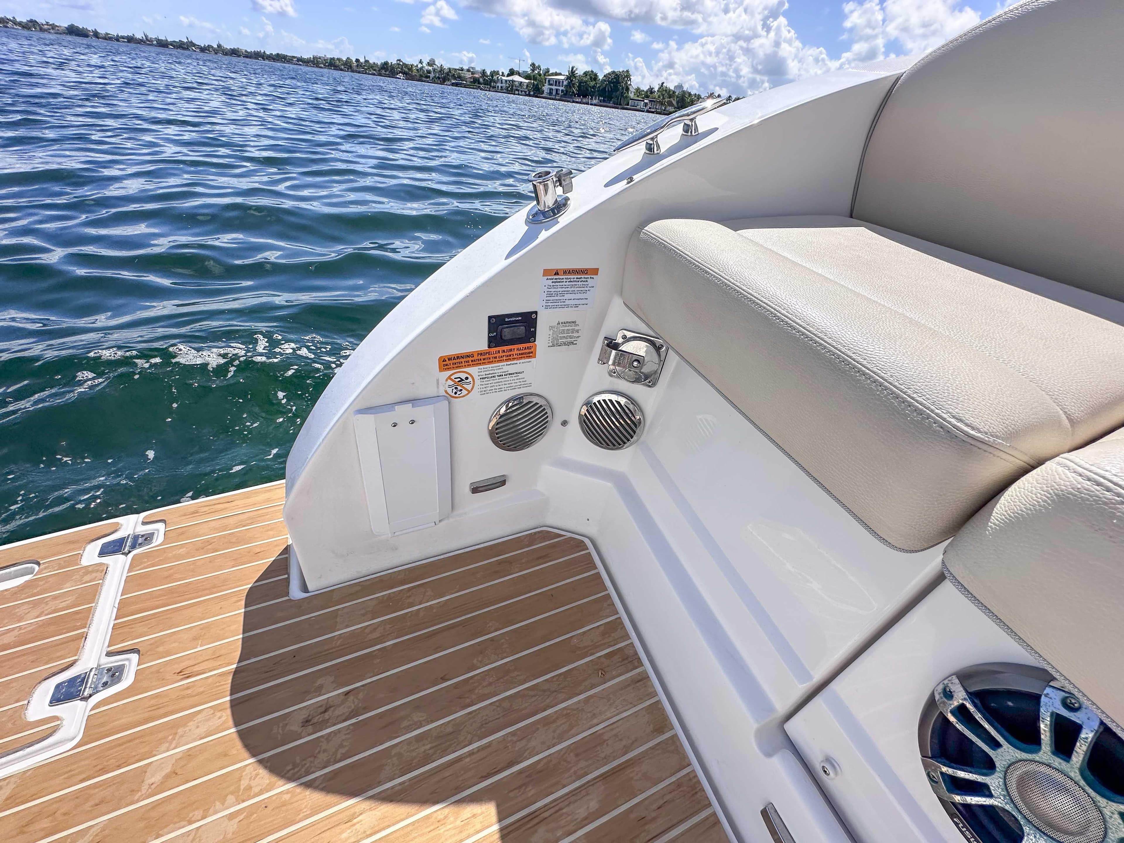 2019 Regal 33 OBX boat with teak deck and cushioned seating by the water.