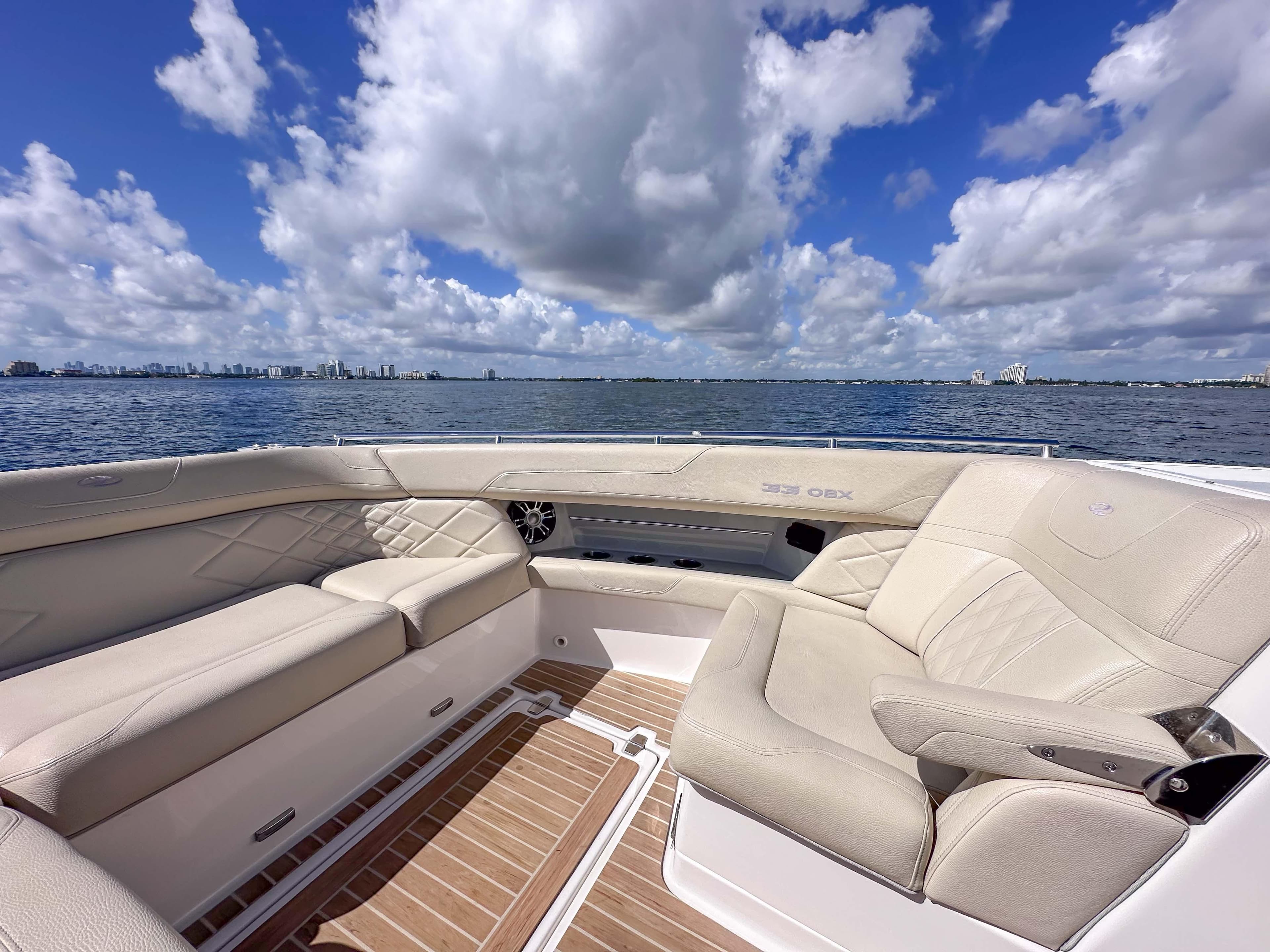 Luxurious seating on 2019 Regal 33 OBX boat with ocean view and cloudy sky.