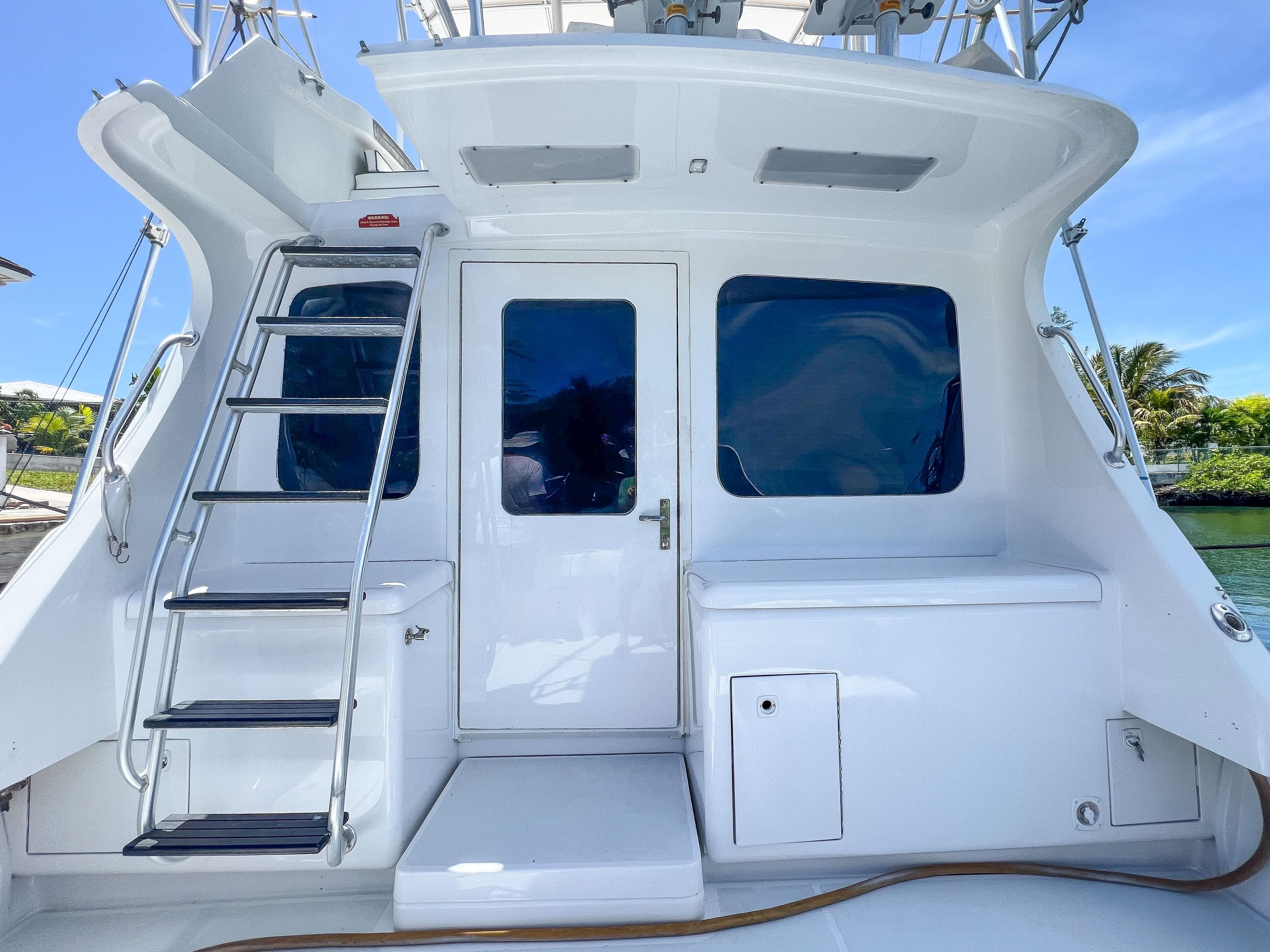 Luhrs 400 Convertible 2000 model, rear view with ladder and door, docked by water.