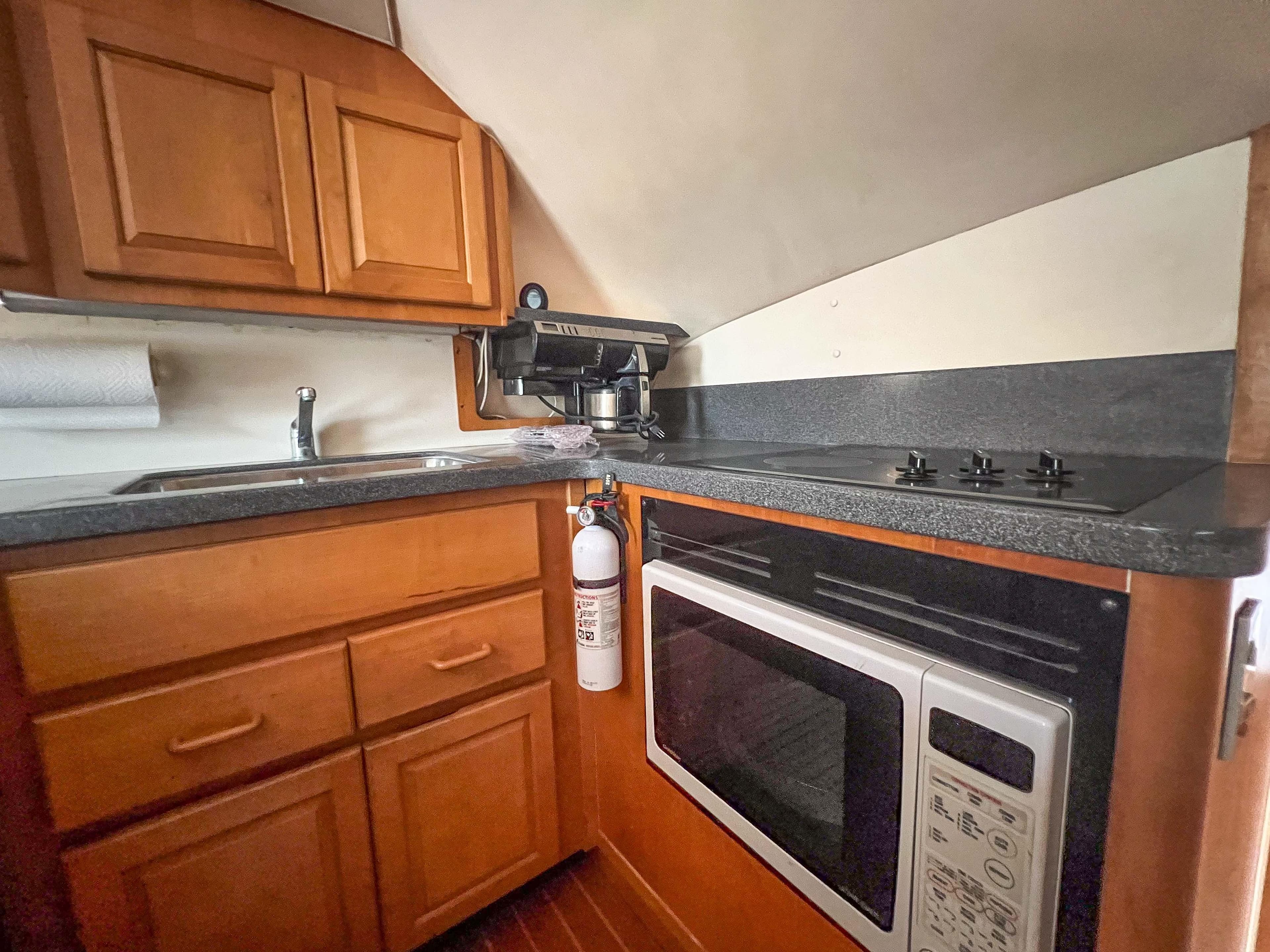 2000 Luhrs 400 Convertible boat kitchen with wooden cabinets, stove, microwave, and sink.